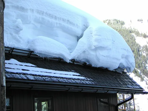 Épaisse plaque de neige en surplomb au bord d'un toit