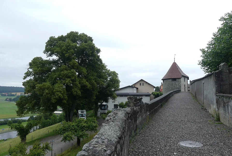 Les remparts et une tour de Romont au-dessus de la campagne glânoise
